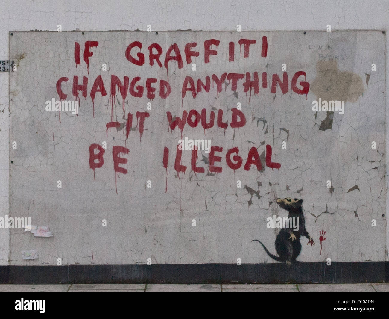 Banksy Graffiti on a white wall 'If graffiti changed anything it would be illegal' over the picture of a rat picking a flower Stock Photo