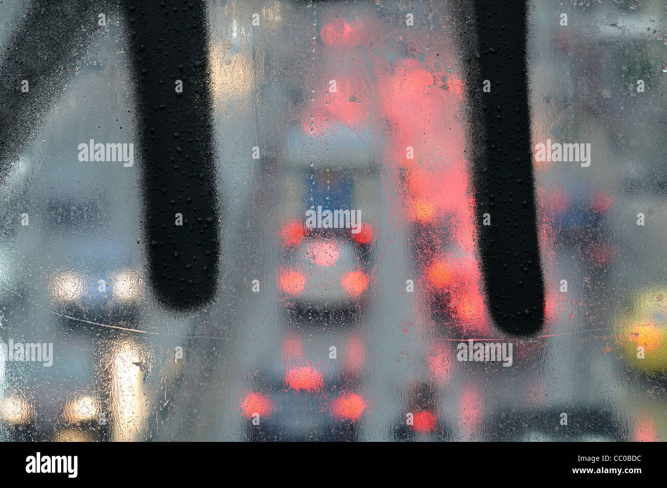 Raindrops macro on glass overpass surface and blurry city traffic lights. Stock Photo