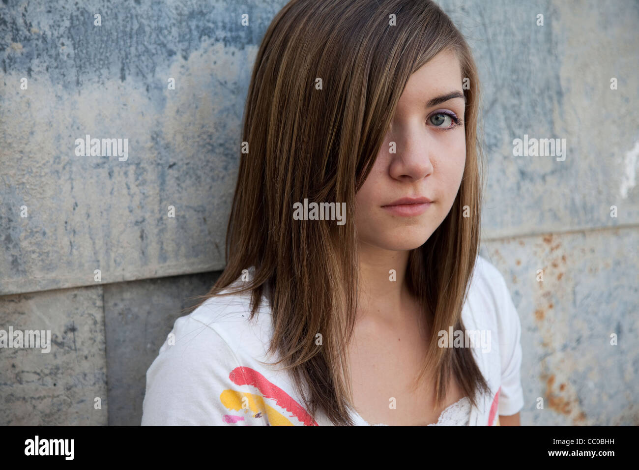 Teenage girl with somber expression against grunge wall Stock Photo