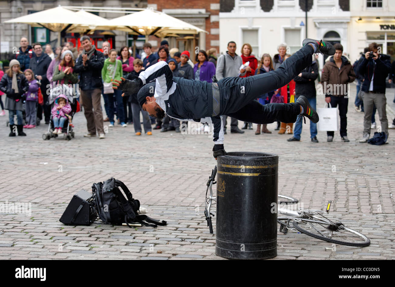 Street entertainer balancing on a littler bin in the Piazza at Covent Garden, London Stock Photo