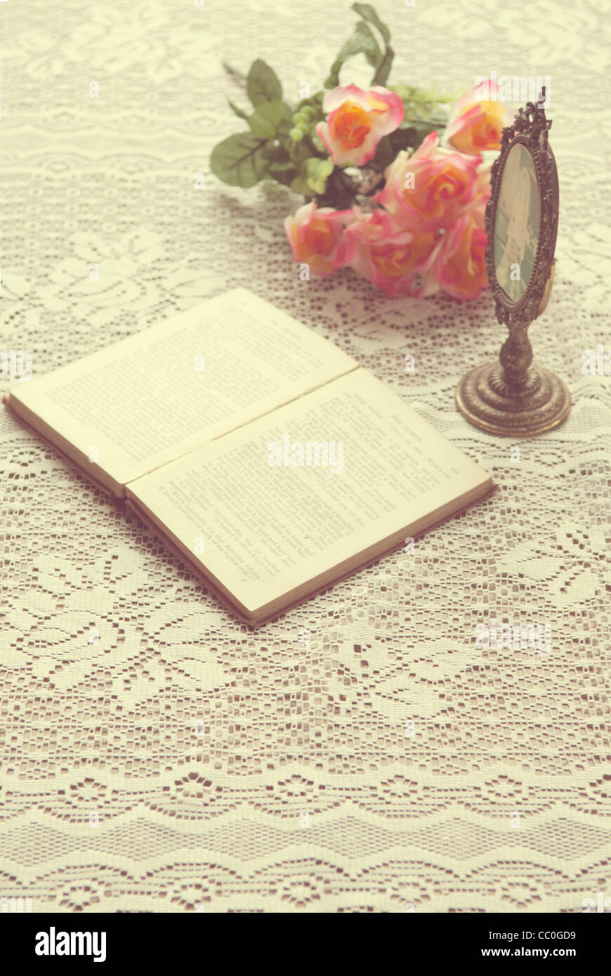 Open book next to oval shaped frame and a bouquet of roses Stock Photo