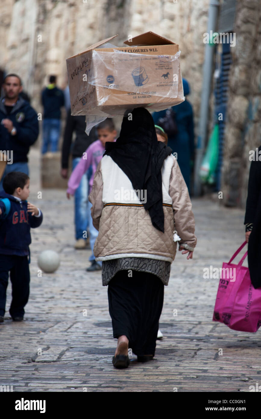 Jerusalem, Old City, Israel, January 05, 2011: Muslim woman walking carry box on her head, El Wad HaGai street Stock Photo