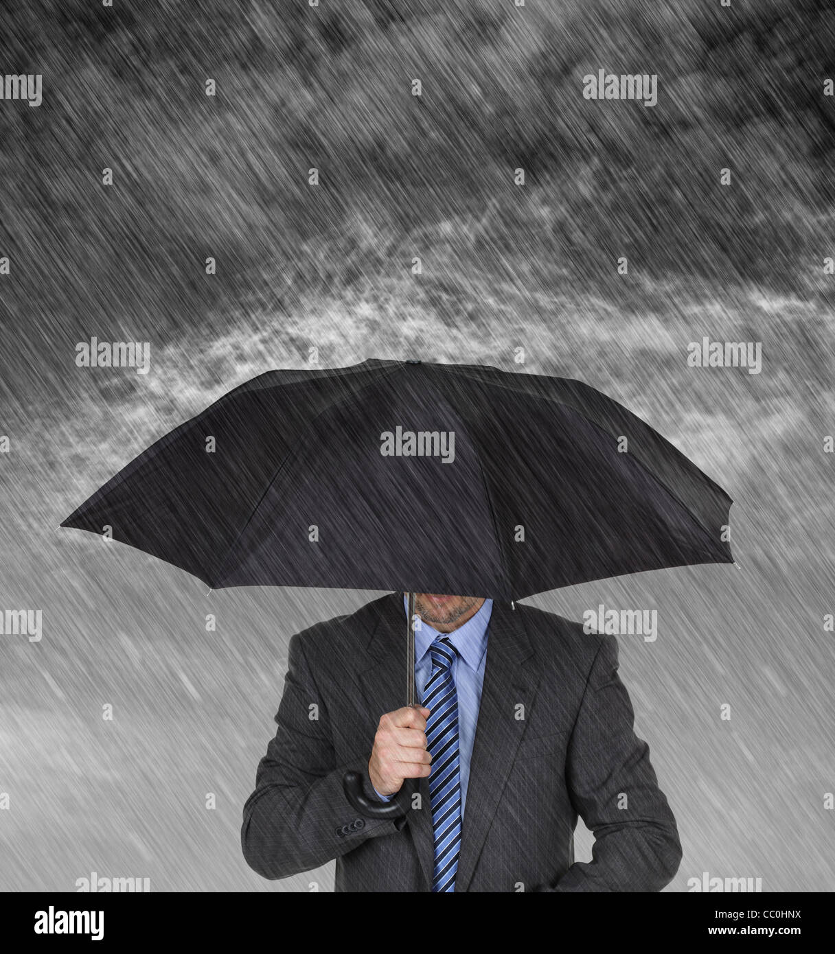 Businessman sheltering from the rain Stock Photo