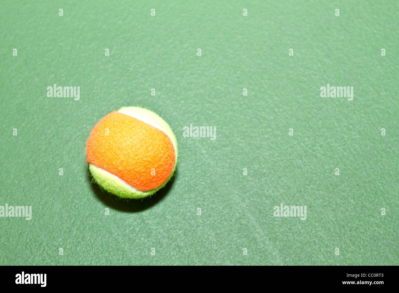 Single tennis ball on court, ready for play, practice, or lessons. Sports symbol is surrounded by copy space. Stock Photo