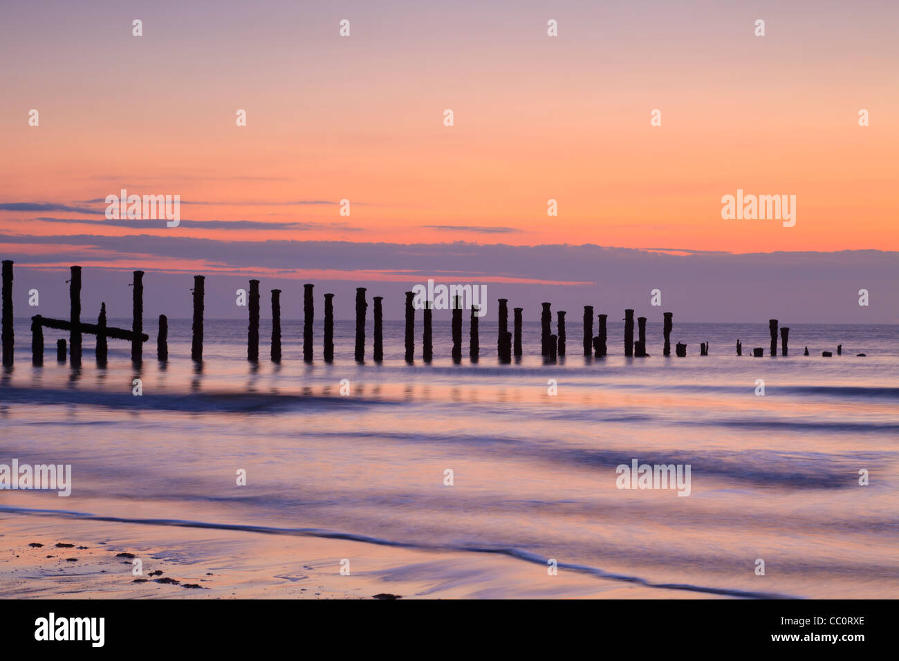 Old sea defences at dawn, smooth water from long exposure. Stock Photo