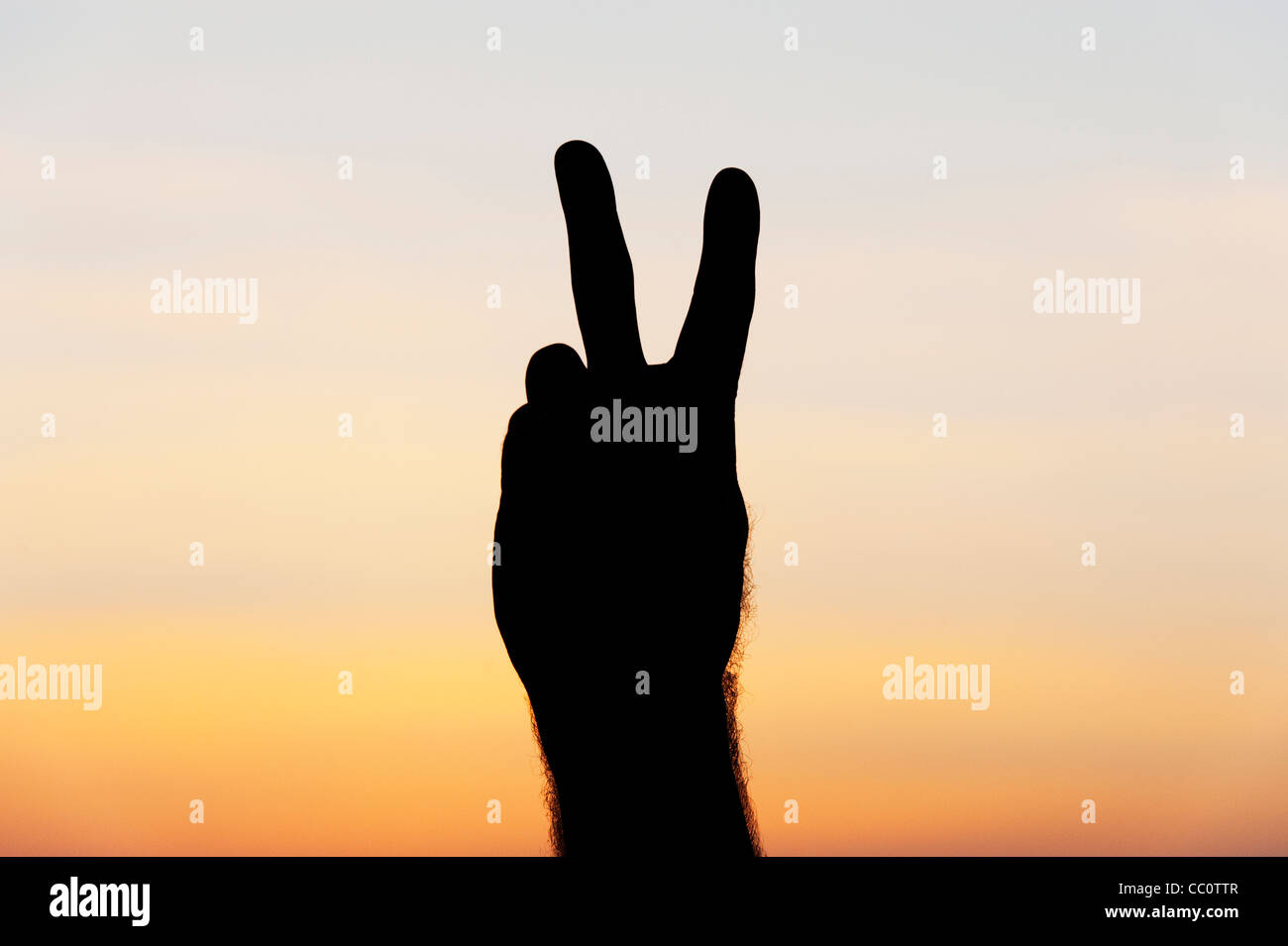 Hand Peace sign silhouette against sunrise sky Stock Photo
