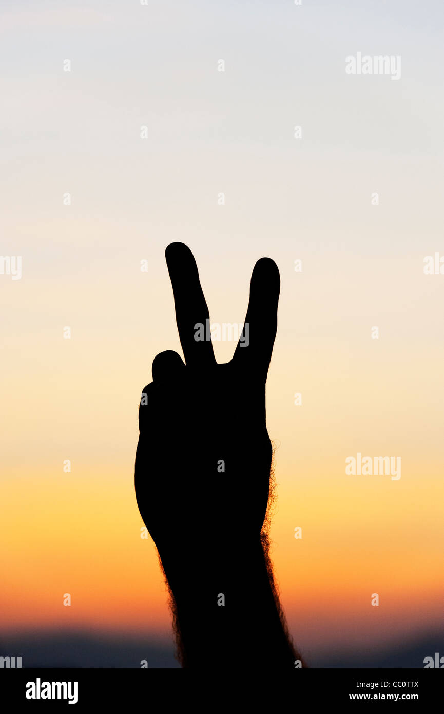 Hand Peace sign silhouette against sunrise sky Stock Photo