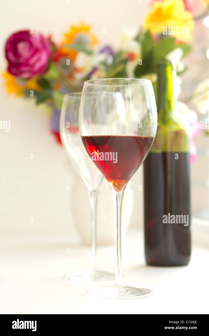 to wine glasses filled with red wine and wine bottle in background Stock Photo