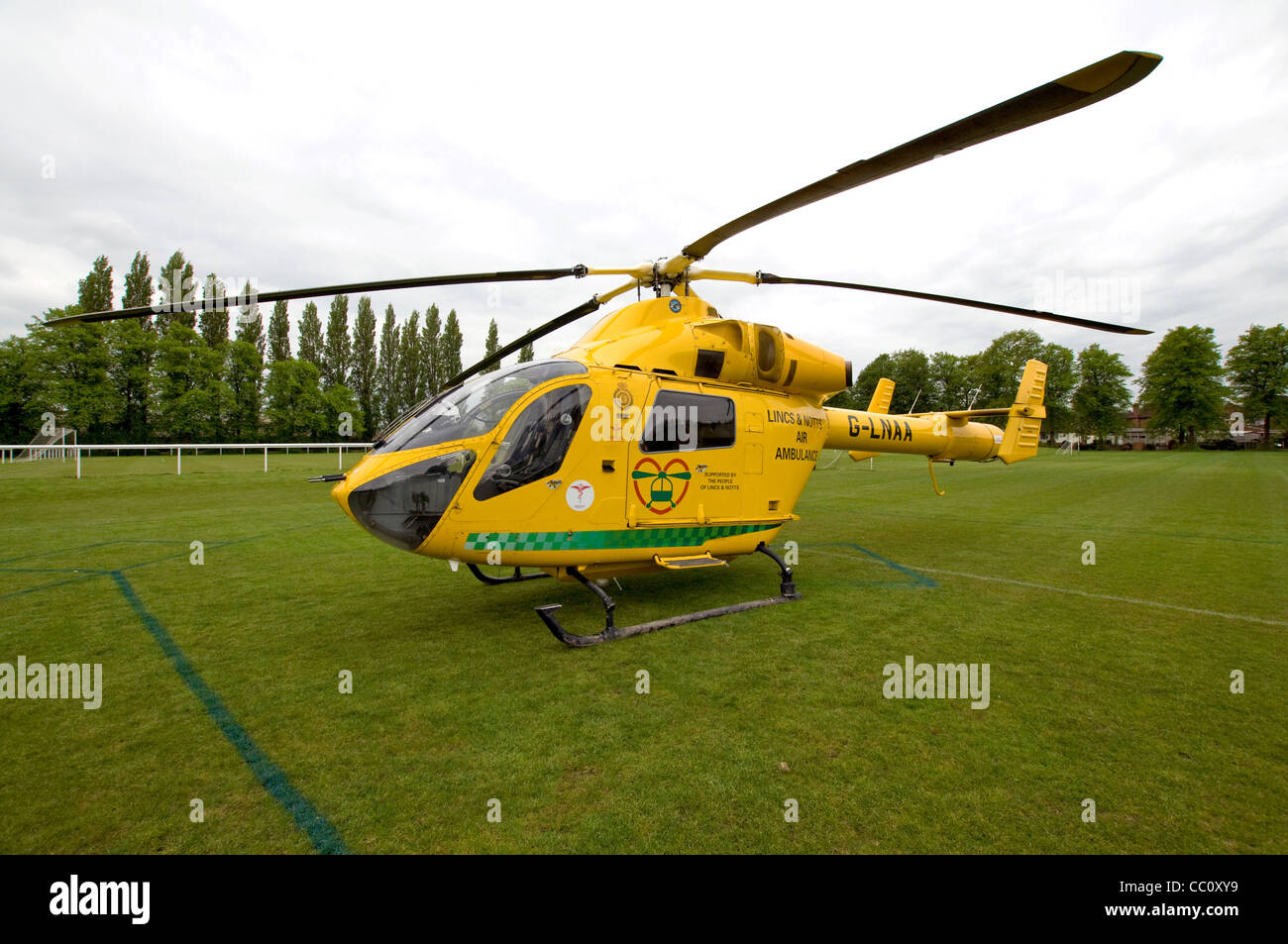 Nottinghamshire air ambulance helicopter landed on a football pitch, trees in the background Stock Photo