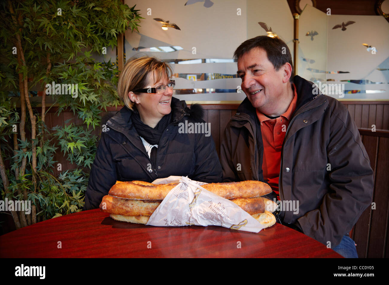 French couple chatting in a café with baguettes on their table. Le Perreux-sur-Marne, Val-de-Marne, France. Stock Photo