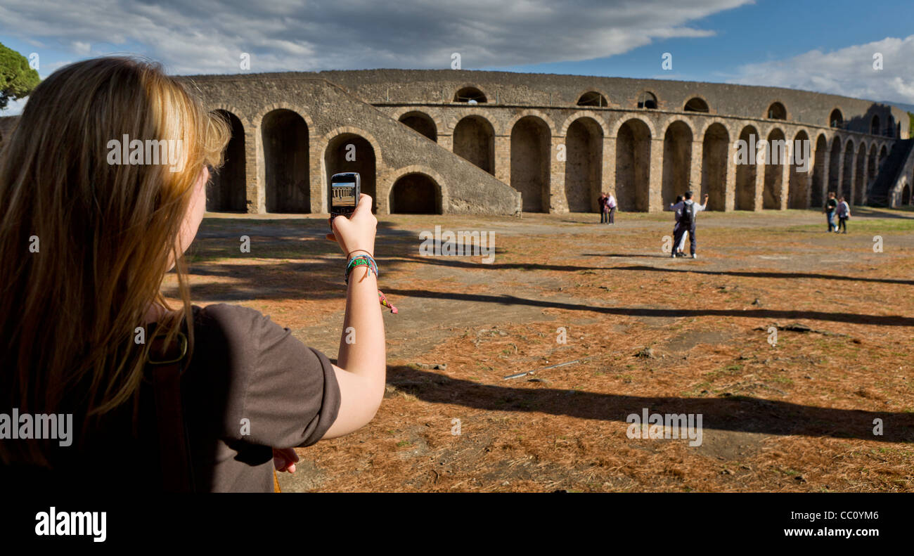 Exterior walls of ancient Roman Amphitheatre, Pompeii, Italy Teen taking photo with a cell phone Stock Photo