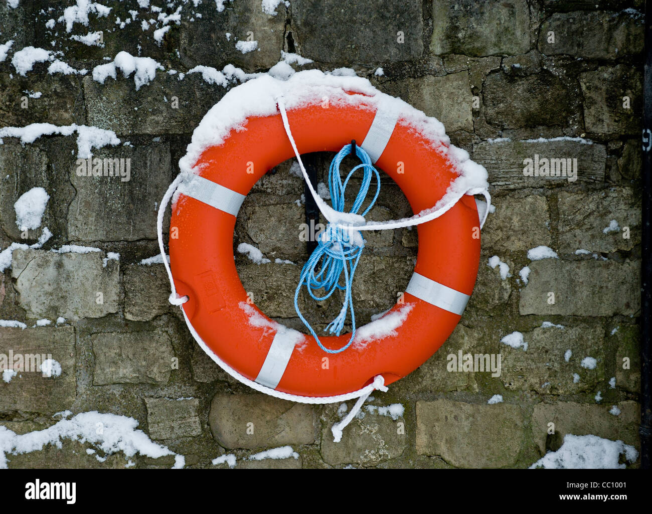 Snow covered lifebelt attached to a wall on the banks of the river Ouse. Stock Photo