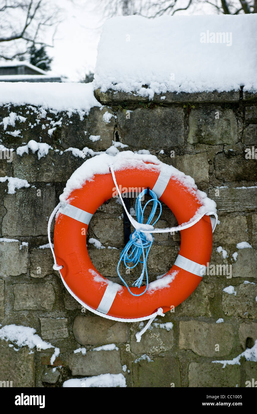 Snow covered lifebelt attached to a wall on the banks of the river Ouse. Stock Photo