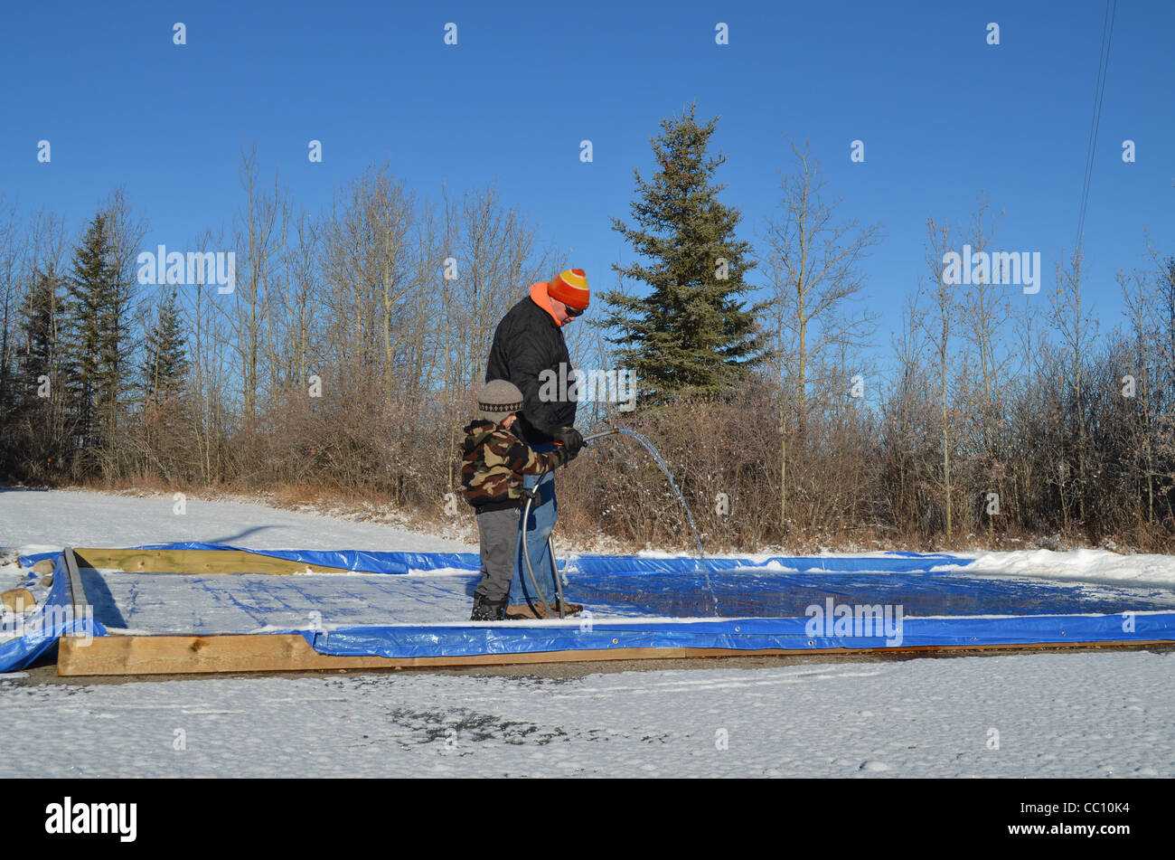Father and son flooding a backyard rink. Stock Photo