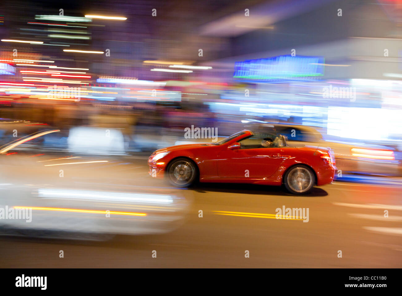 Red sport car at the crossroads. Manhattan street in the night. Stock Photo