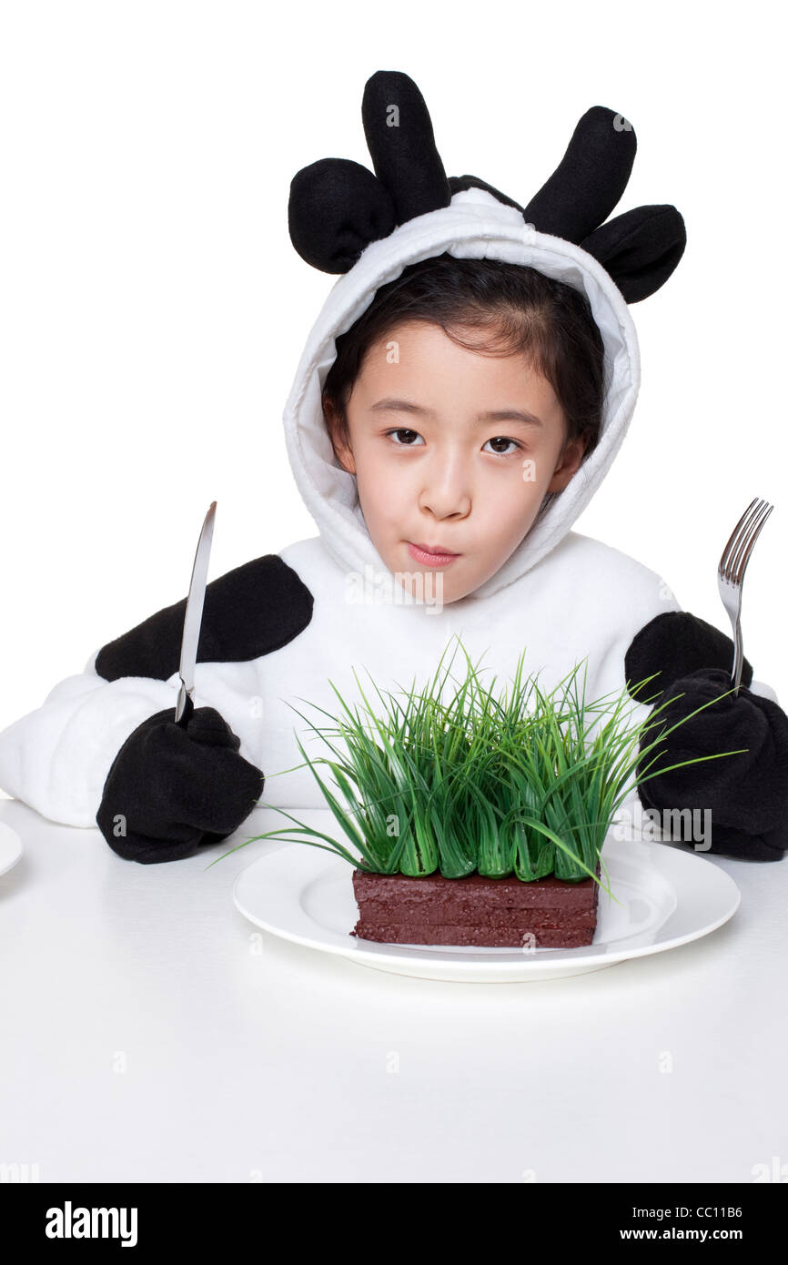 Girl in a cow costume with a serving of grass on her plate Stock Photo