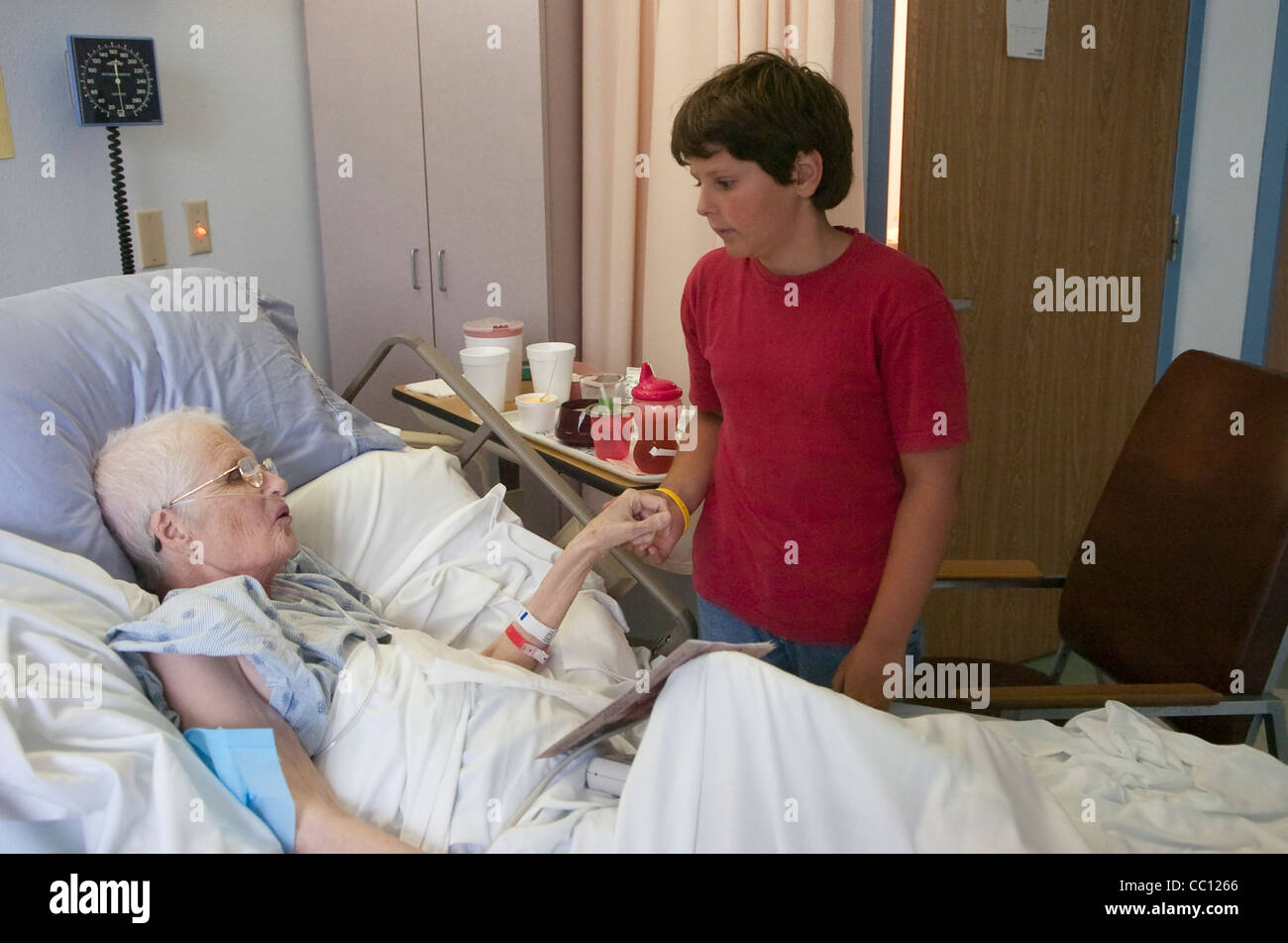 73 year old Anglo woman hooked up with oxygen  receives visit from grandson which she lay in hospital bed with terminal cancer Stock Photo