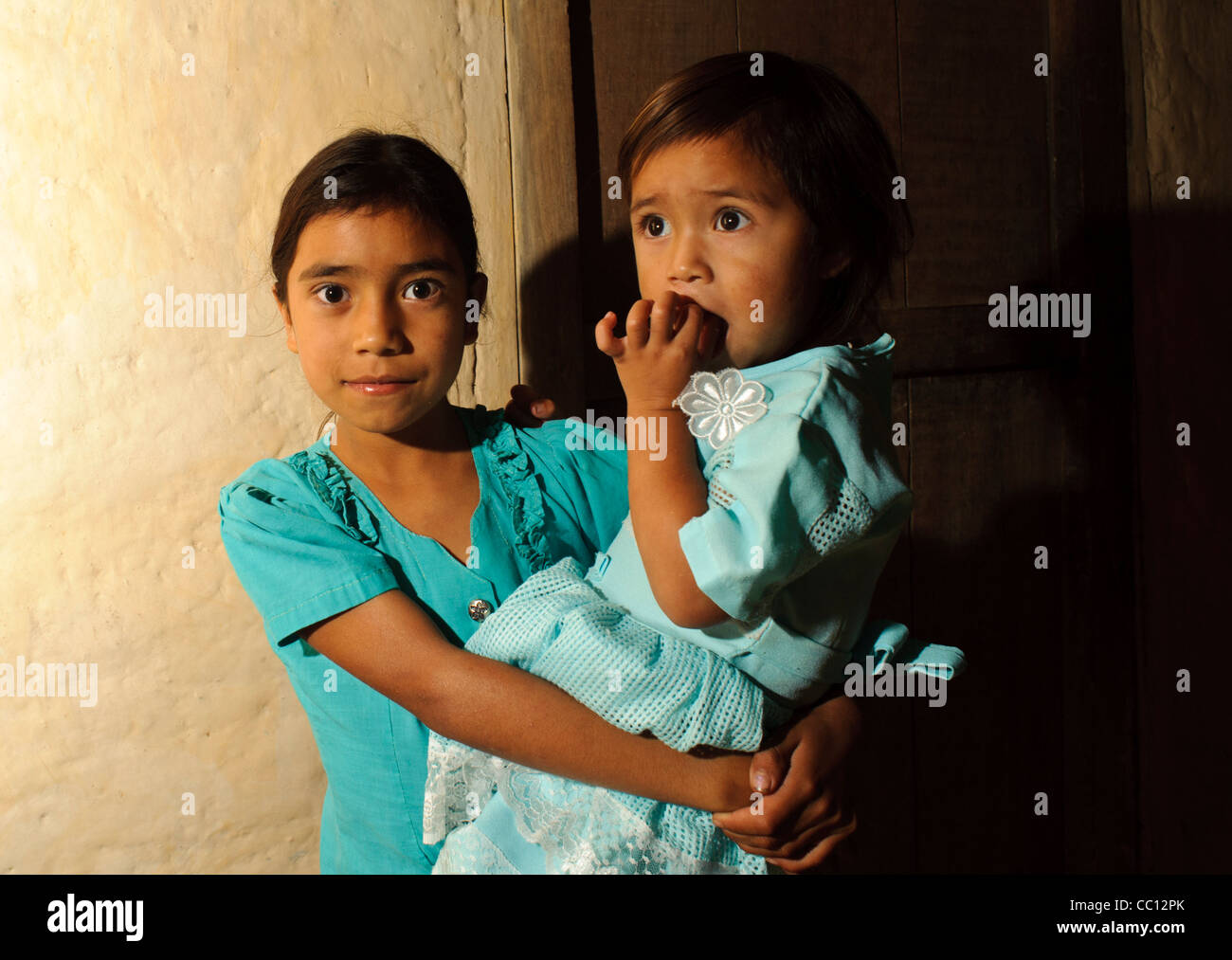 Two young girl children of a poor campesino in the mountains of Honduras. Older one carrying younger one Stock Photo