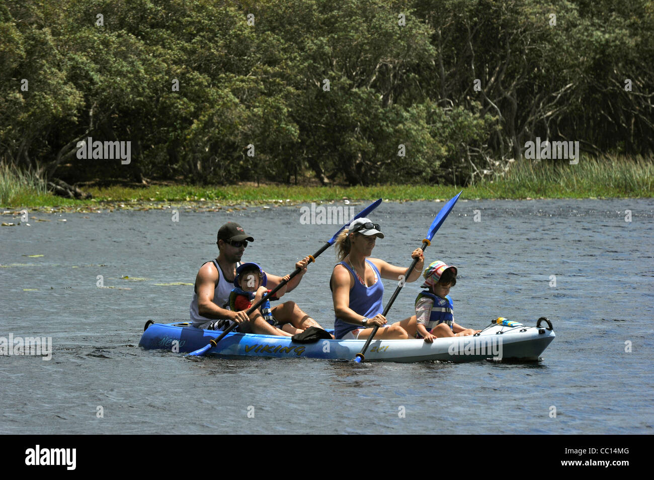 A Family paddle a canoe together on a Lake Stock Photo