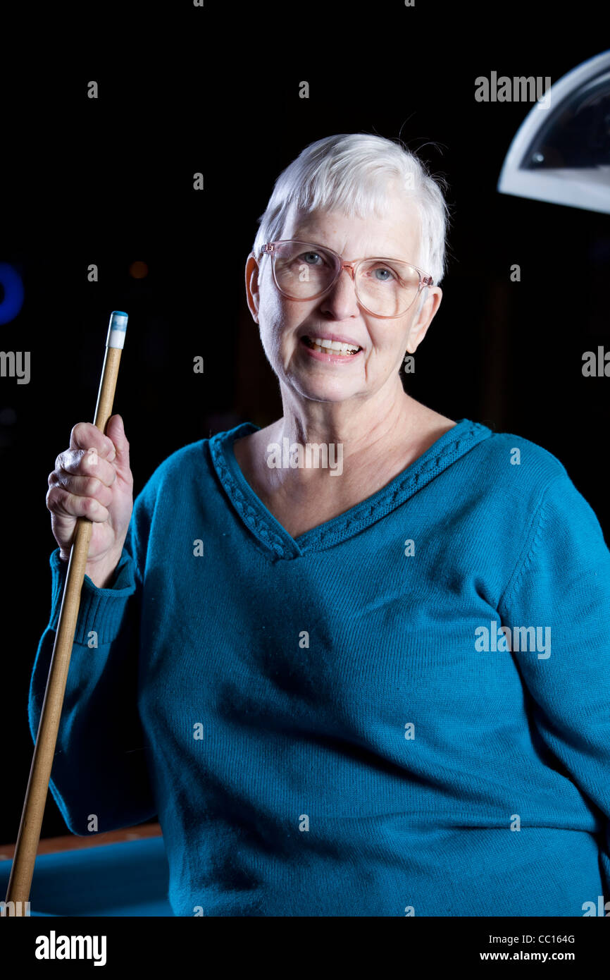 Smiling woman holding a pool cue by a pool table Stock Photo
