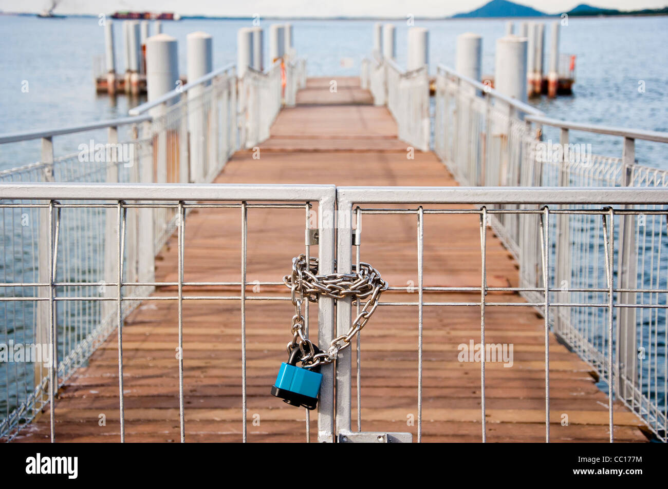 A chain lock upon a gate leading to a pier in the distance Stock Photo
