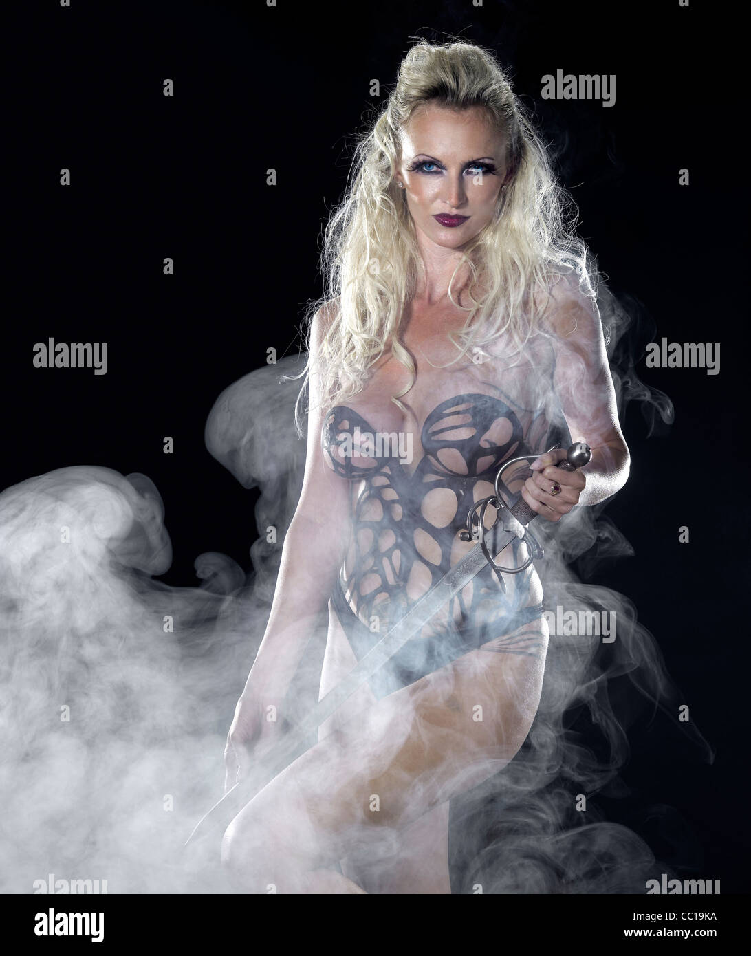 bodypainted blond woman posing in dark back and some fog Stock Photo