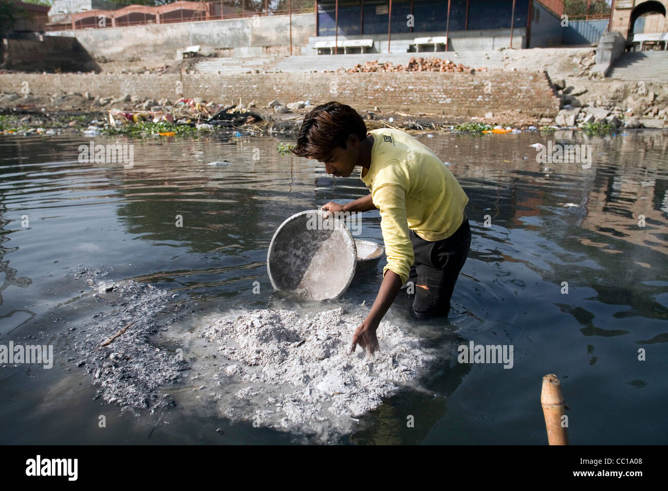A man tips ashes of a cremation into the Yamuna River, Nigambodh Ghat