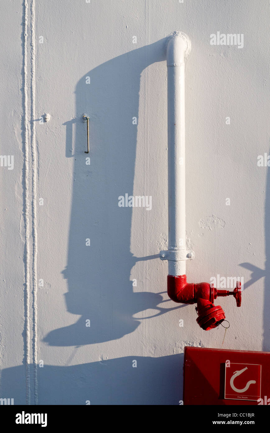 Ship hose valve, painted red on a white background, photographed on board the Fred Olsen cruise ship MS Boudicca. Stock Photo