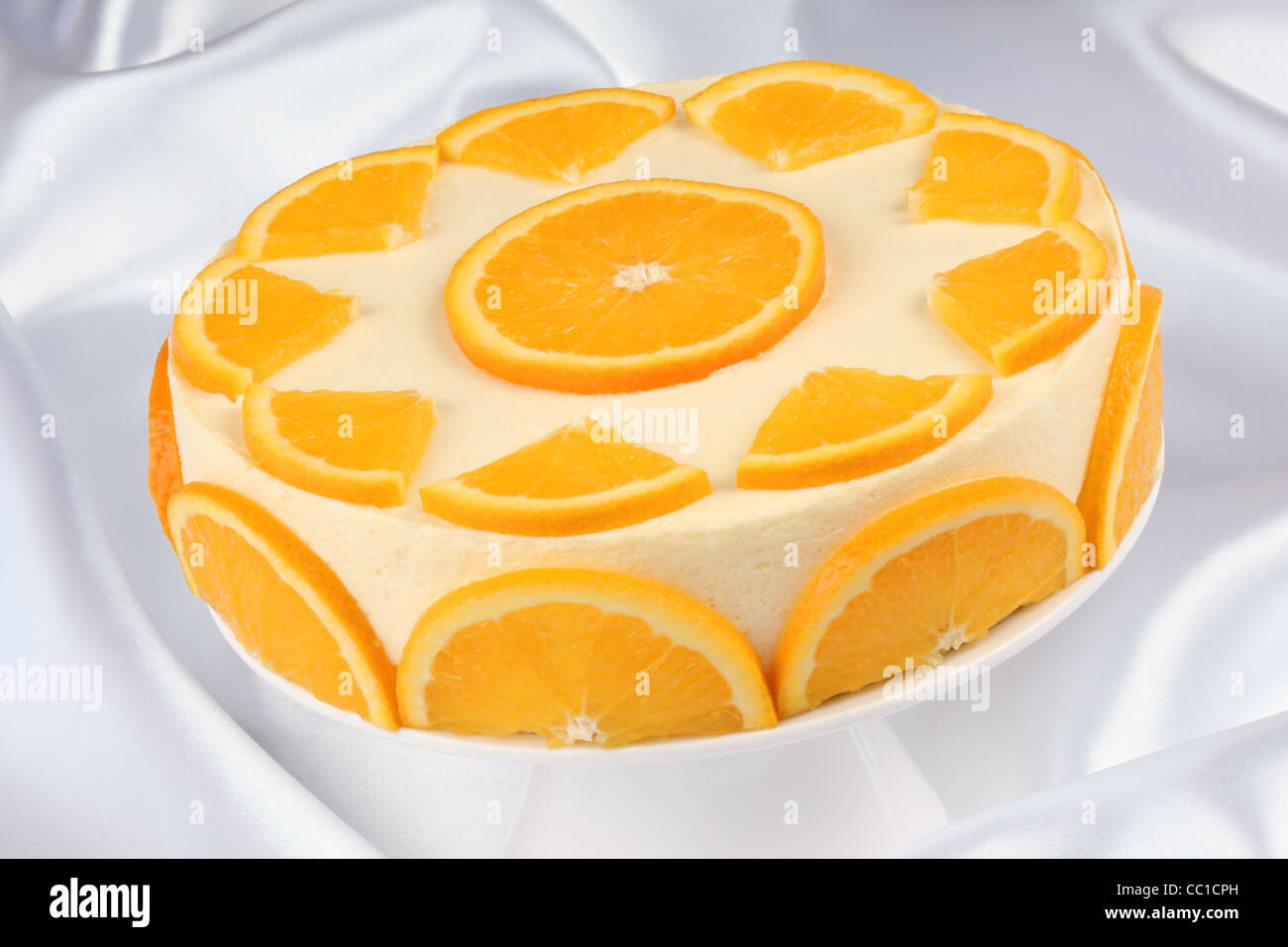 Orange bavarian cream (bavarese) on a white porcelain cake stand Stock Photo