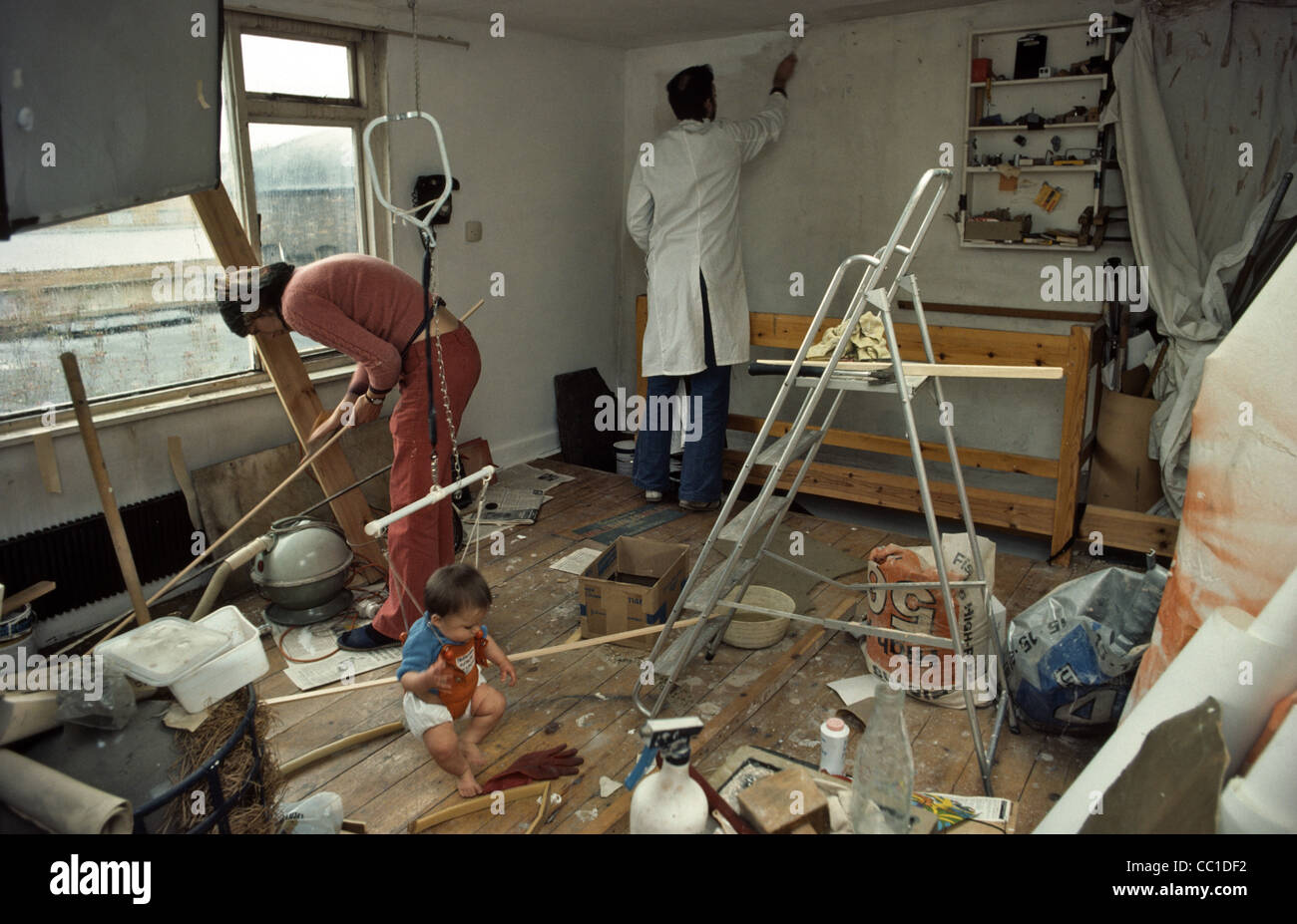 Parents wallpapering room while taking care of baby Stock Photo Alamy