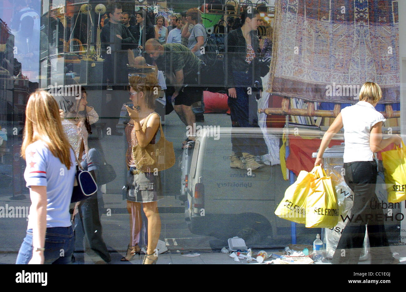 reflections in a shop window with people carrying bags talking to friends and walking by Stock Photo