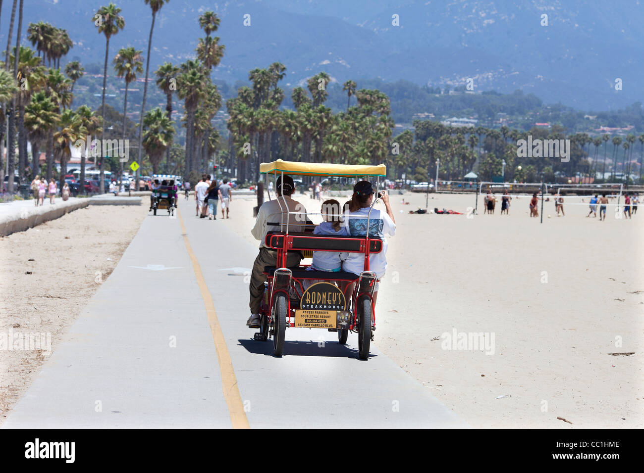Family in a Deuce Coupe peddle bicycle on the promenade at Santa Barbara beach California Stock Photo