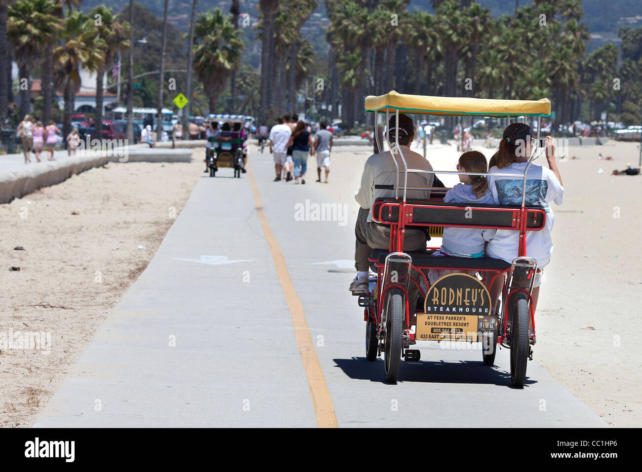 Family in a Deuce Coupe peddle bicycle on the promenade at Santa Barbara beach California Stock Photo