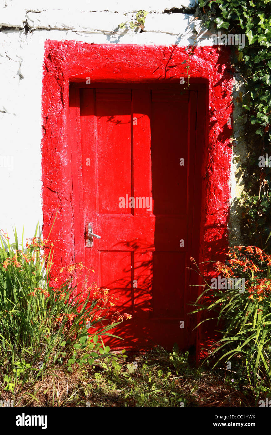 Red painted door and montbretia  flowers. Donegal. Ireland Stock Photo