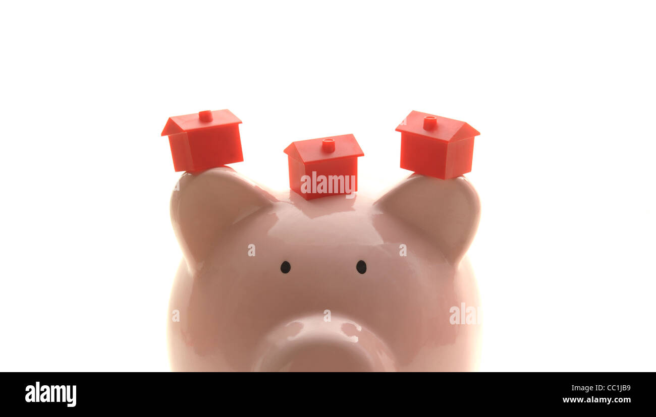 PIGGY BANK WITH MODEL HOUSES RE HOUSING MARKET HOME BUYERS FIRST TIME BUYERS MORTGAGES SELLING SAVINGS  RISING LIVING COSTS UK Stock Photo