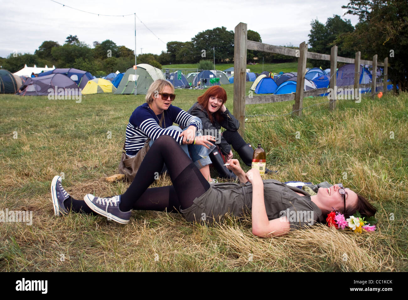 Three women friends joke and laugh in a field next to a mobile sound system at the Standon Calling Festival in Hertfordshire, UK Stock Photo