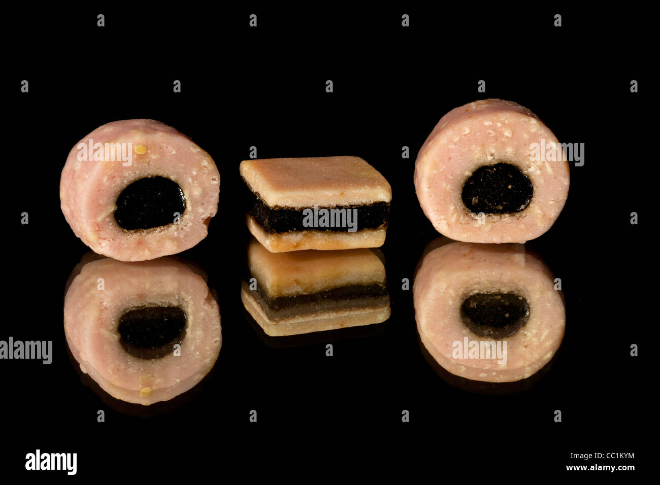Pink liquorice allsorts sweets on a black background with reflections