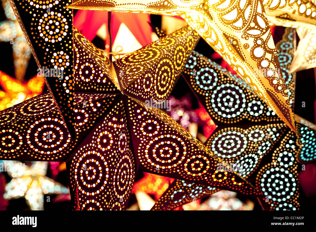 Bright colourful and dynamic lit up paper stars hang in a Christmas market in Munich, Germany. Stock Photo