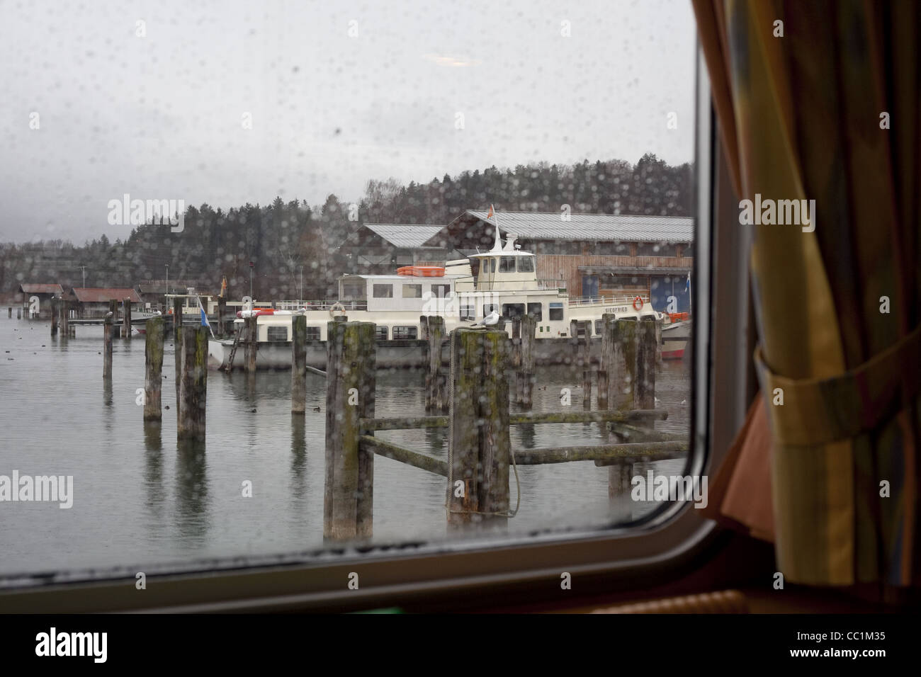 Horizontal image of the boat docks on the Chimsee lake, from the window of the ferry on a rainy Winter afternoon. Stock Photo