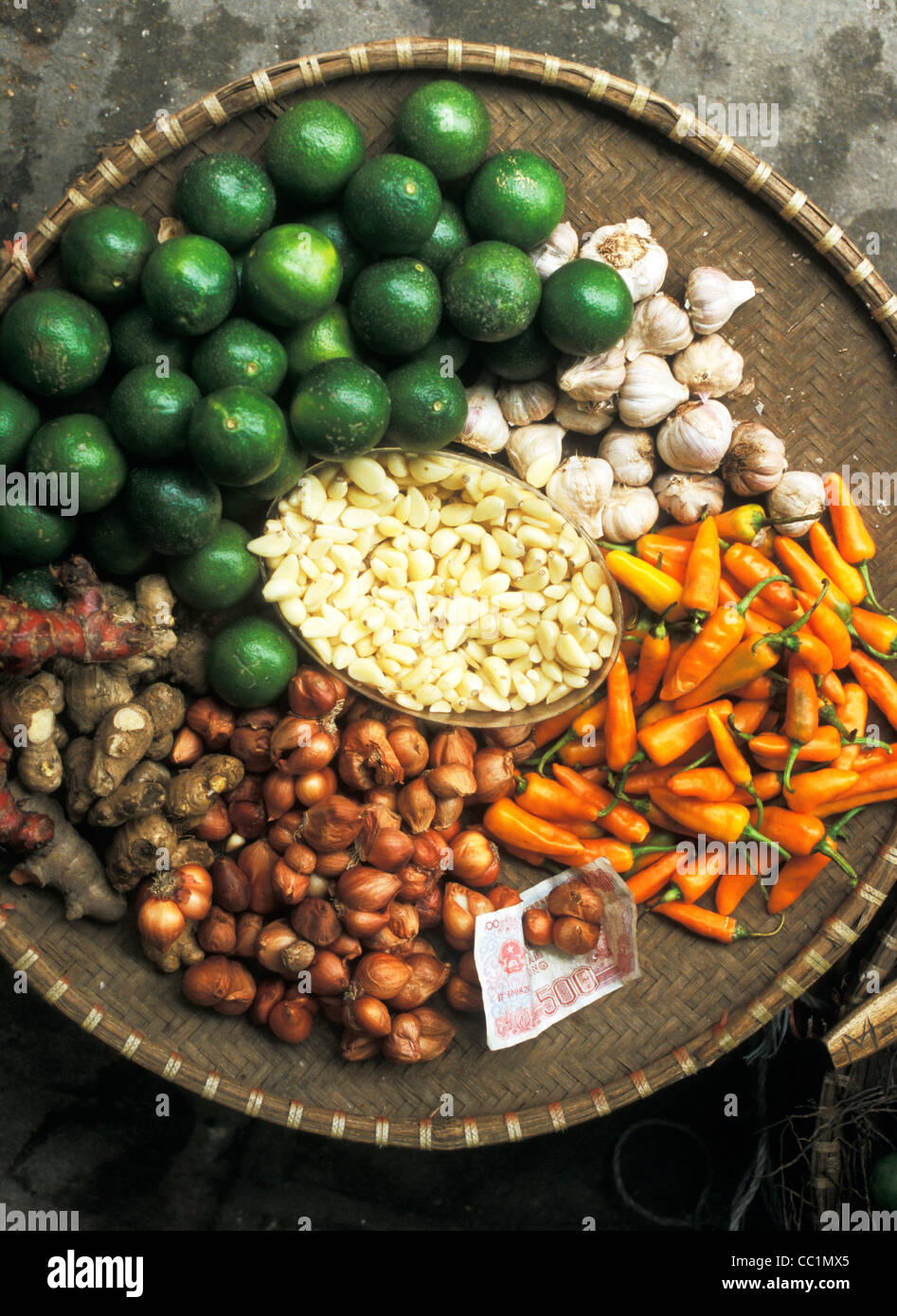 Market vendor's wicker tray holding limes, garlic and chilli peppers, Hanoi, Vietnam Stock Photo
