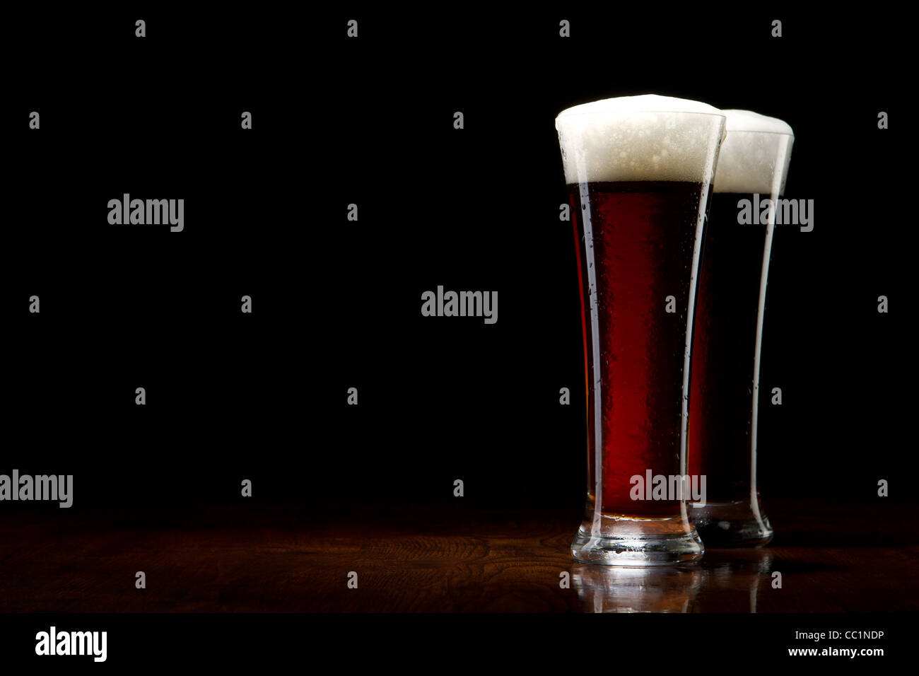 two Beer into glass on a black and wooden table Stock Photo