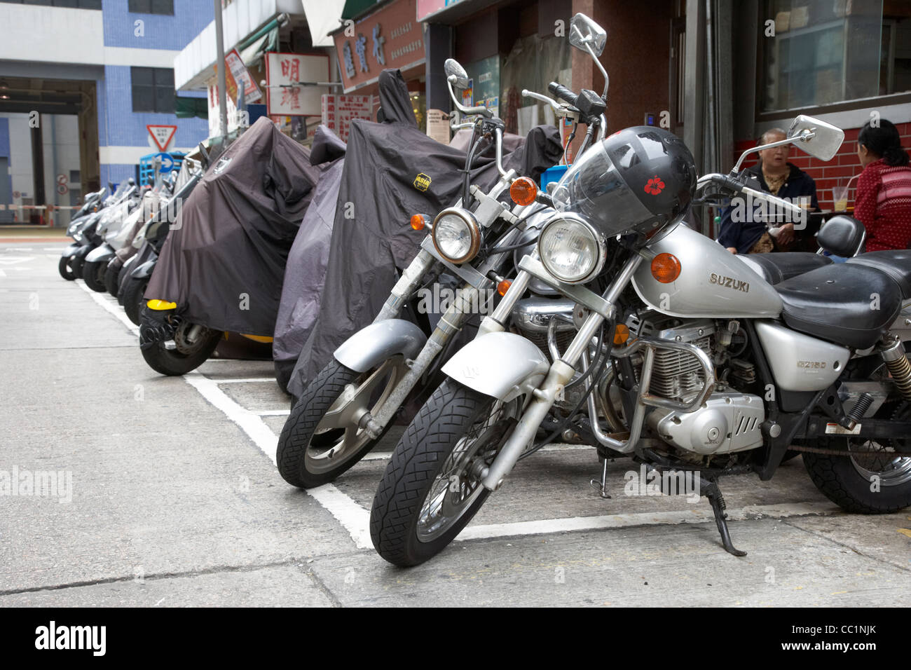 row of motorcycles motorbikes parked on the side of a street some covered in hong kong hksar