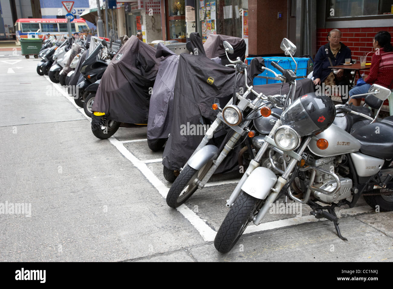 row of motorcycles motorbikes parked on the side of a street some covered in hong kong hksar