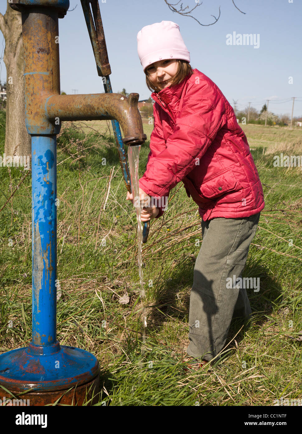 little girl and old water pump Stock Photo