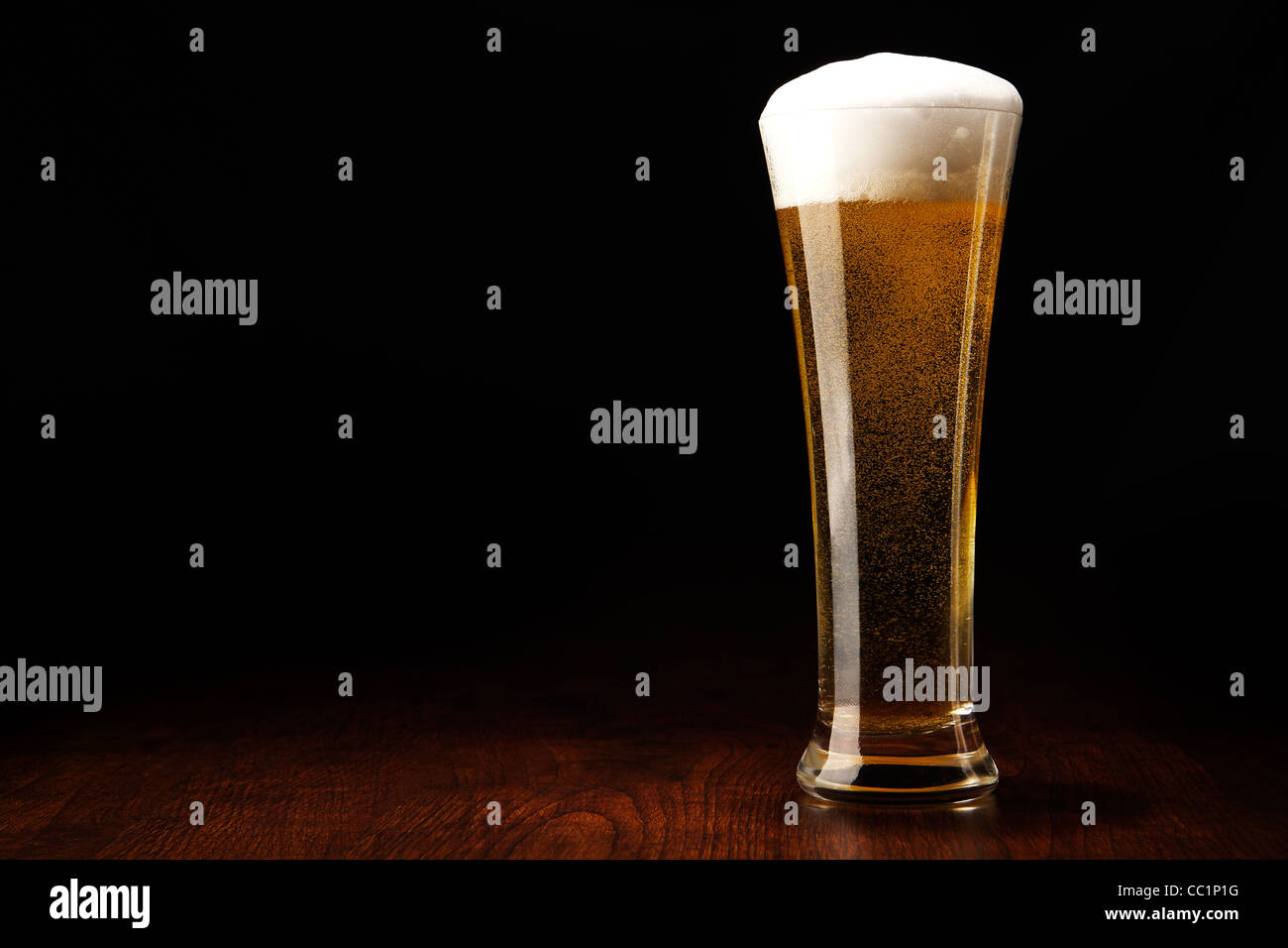 Beer into glass on a black and wooden table Stock Photo