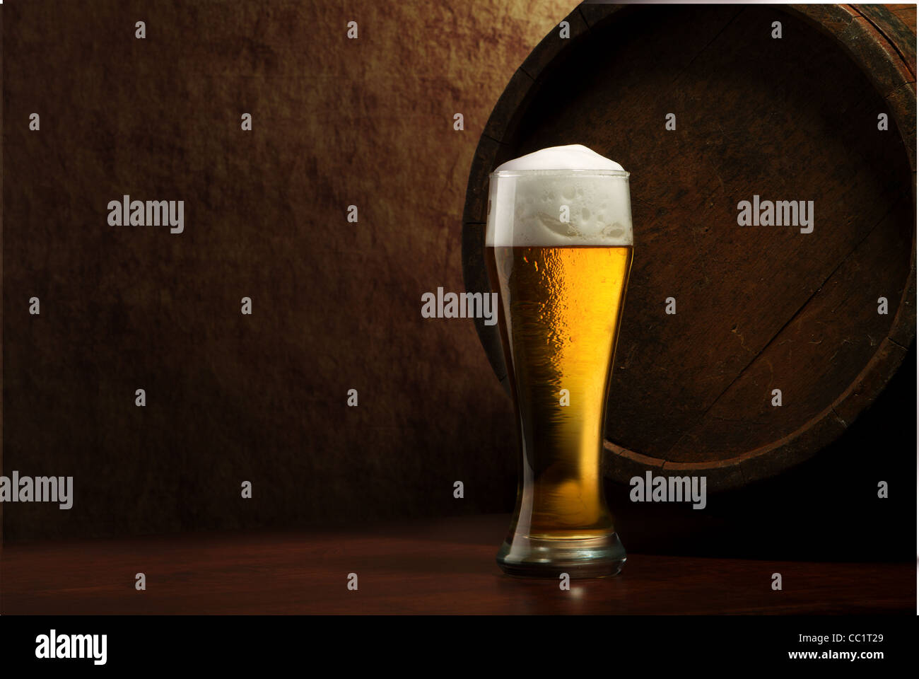Beer into glass on a old stone and old barrel Stock Photo