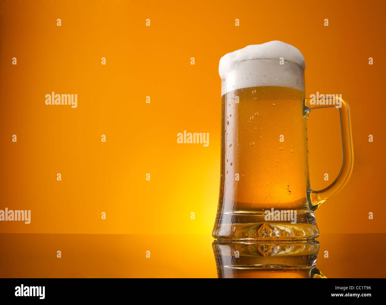 Glass of beer close-up with froth over orange background Stock Photo