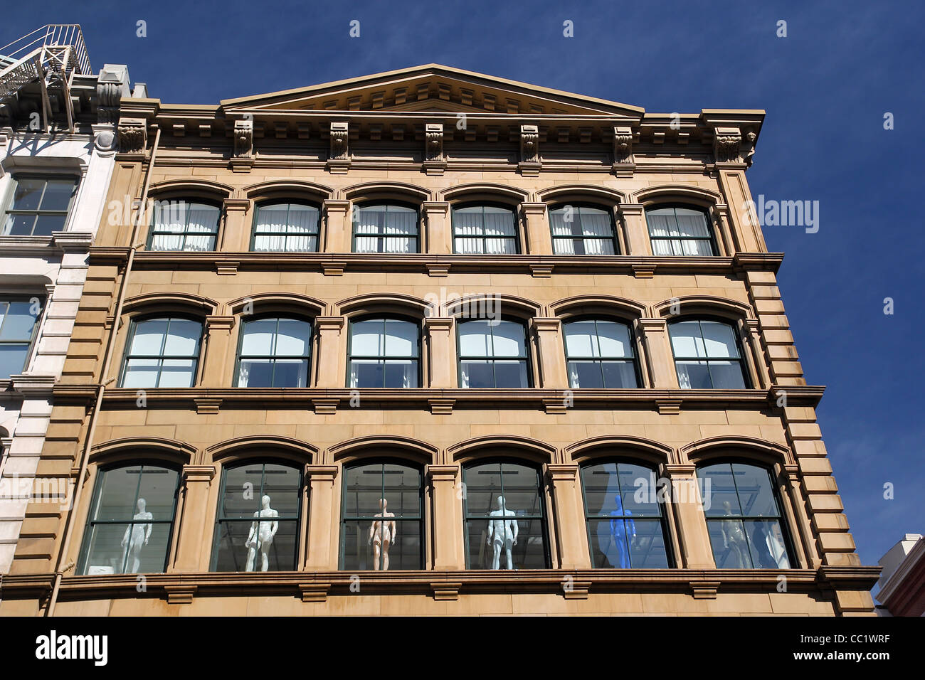 Human figures stand in the windows of a building in Manhattan's Soho