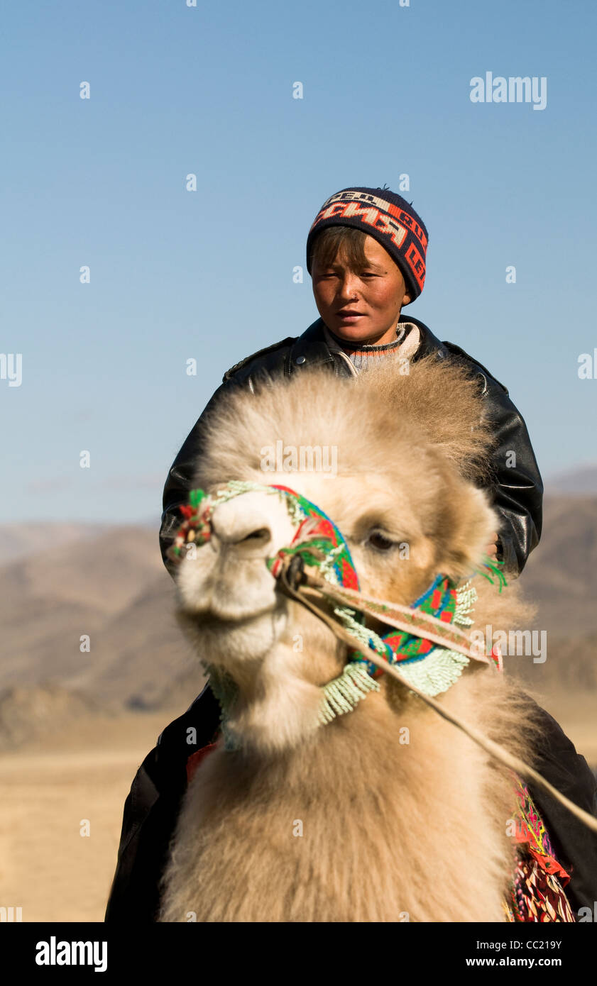 A Kazakh boy riding a double hump camel in the Altai region of Western ...