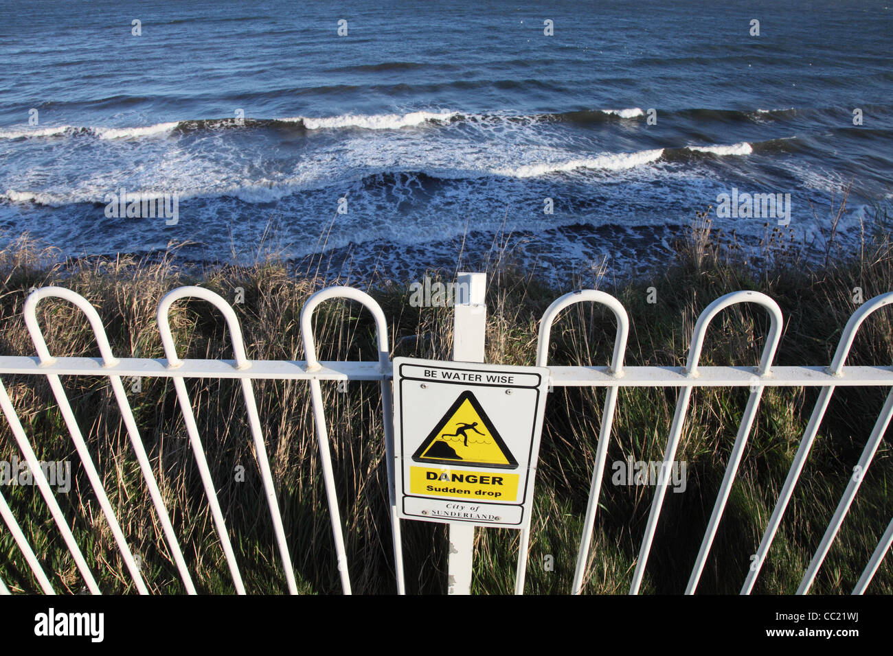 Sign or notice Danger Sudden Drop, be Water Wise, above cliffs Roker north east England, UK Stock Photo